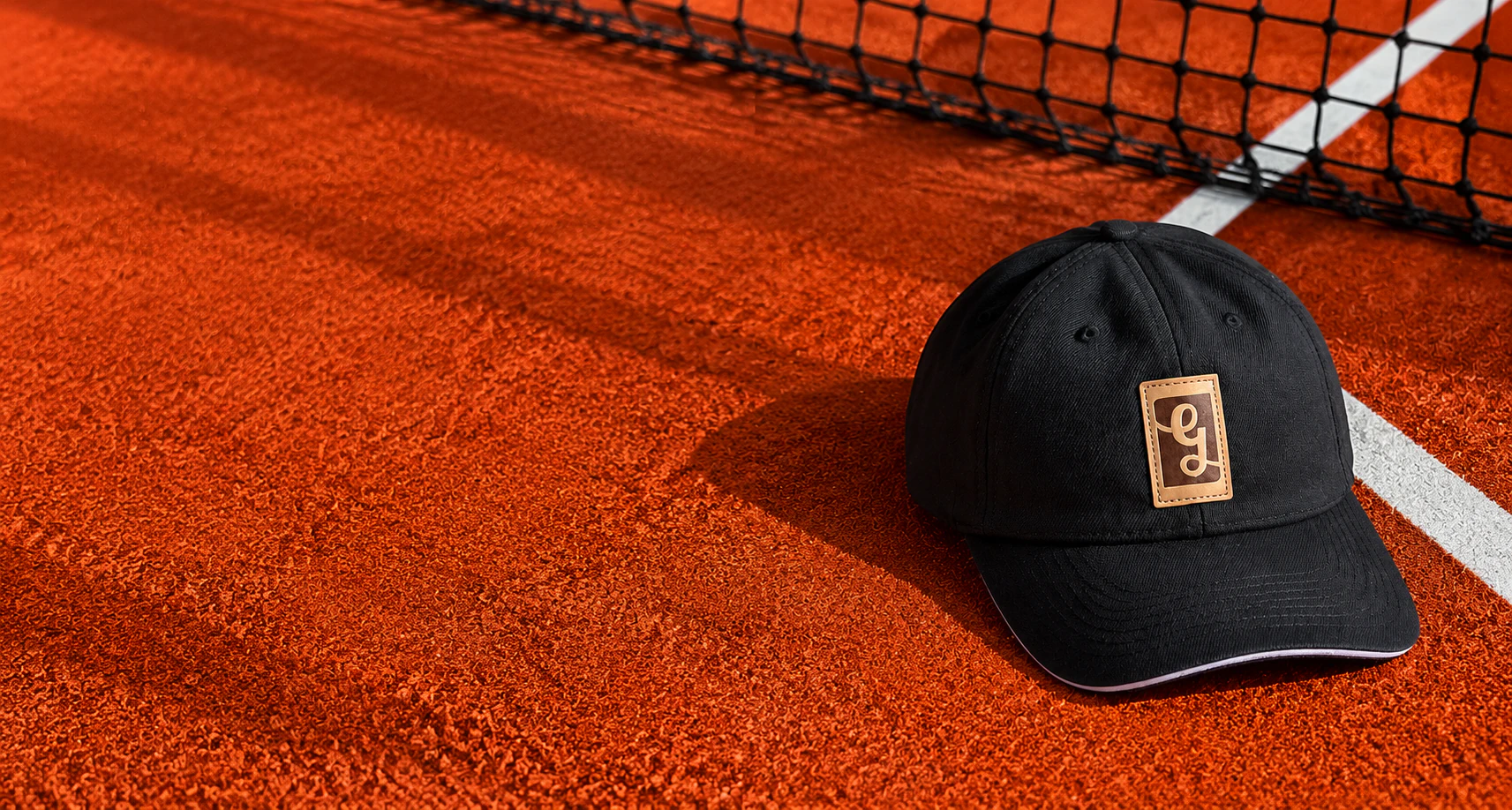 Gorra negra Goldenslip sobre cancha de arcilla